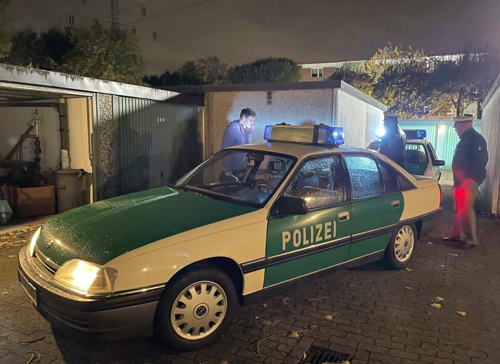 Die Nachtszene an einem Garagentrakt in Hamburg-Horn vor einer Garage im Blaulichtschein unseres Opels Omega und des Ford Sierra – letzte Anweisungen durch den Regisseur an die beiden PMC’ler