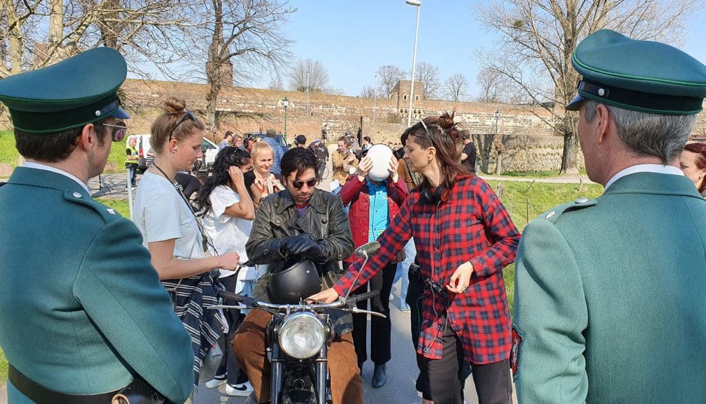 Die Regisseurin Mira Thiel (rotes Hemd) gib letzte Anweisungen an Omid Memar (Freund Bijan, Freund von Winne) anlässlich der Verkehrskontrolle mit dem Motorrad in der ARD Serie "Unsere wunderbaren Jahre"
