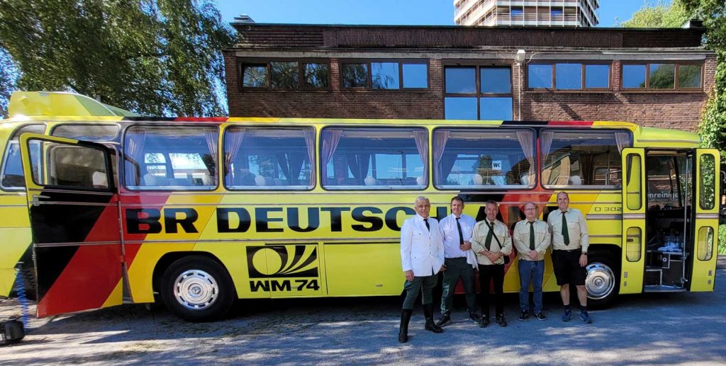 Das Team aus dem Polizeioldtimer Museum Marburg vor dem Dreh zur RTL-Serie 'Gute Freunde - Der Aufstieg des FC Bayern' vor dem Nationalmannschafts-Bus der Fußball-WM 1974