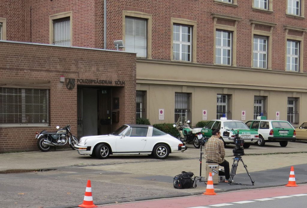 Die historischen Polizeifahrzeuge aus dem Polizeioldtimer Museum Marburg stehen im Hintergrund beim Dreh zum RTL-Film "Entführt - 14 Tage Überleben" vor dem Polizeipräsidium Köln, im Vordergrund der Porsche der Familie Erlemann
