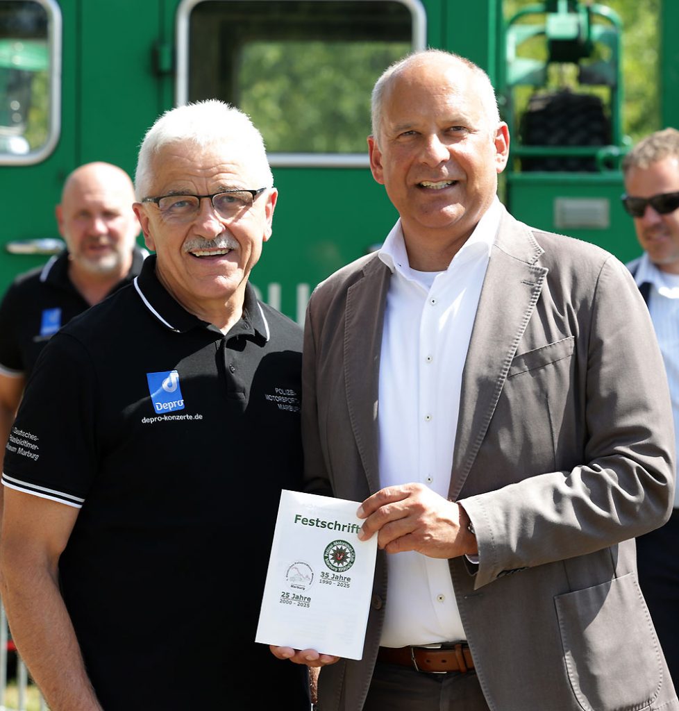 Innenminister Roman Poseck bekam abschließend auch noch die Festschrift zum Doppel-Jubiläum vom PMC-Vorsitzenden Eberhard Dersch überreicht