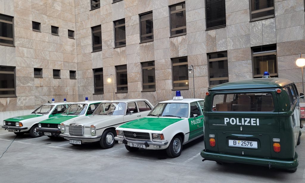 Die Filmfahrzeuge für den Dreh von Ku'damm 77 im Hinterhof der fiktiven Polizeidirektion, rechts die beiden Fahrzeuge aus dem Polizeioldtimer Museum, der VW T2 und der Opel Rekord D