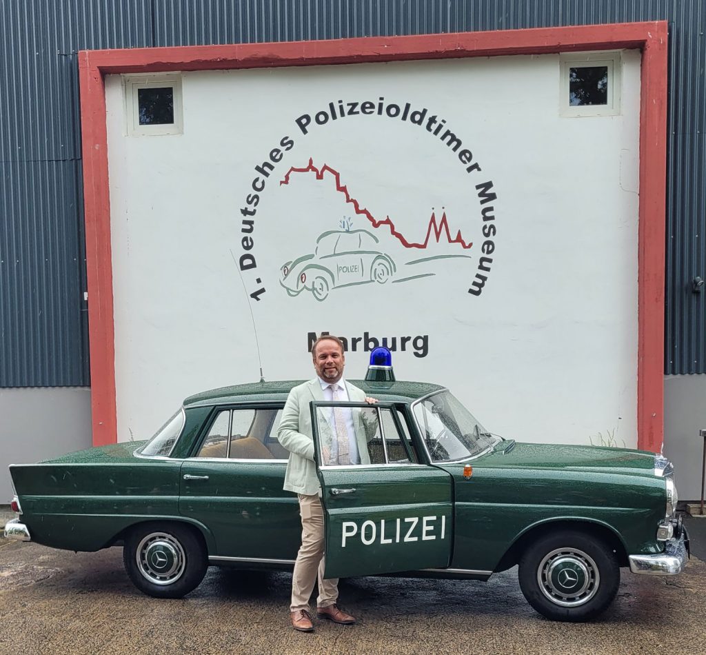 Kunst- und Kulturminister Timon Gremmels vor dem Mercedes Benz 190 aus dem Polizeioldtimer Museum Marburg